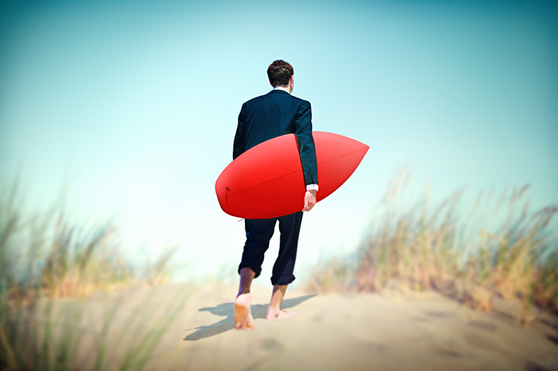 Business man on incentive trip with a surfboard on the beach, Planify, Group Travel Itinerary Solution